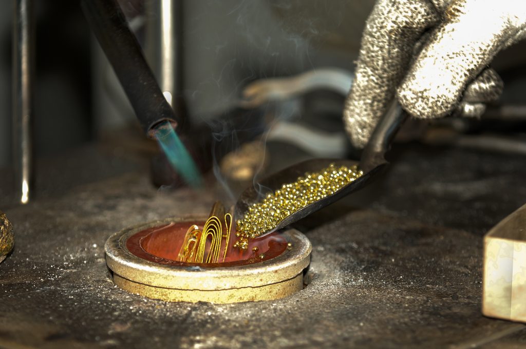 image of person melting gold into a receptacle