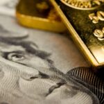 close up of gold bullion and hundred dollar bill