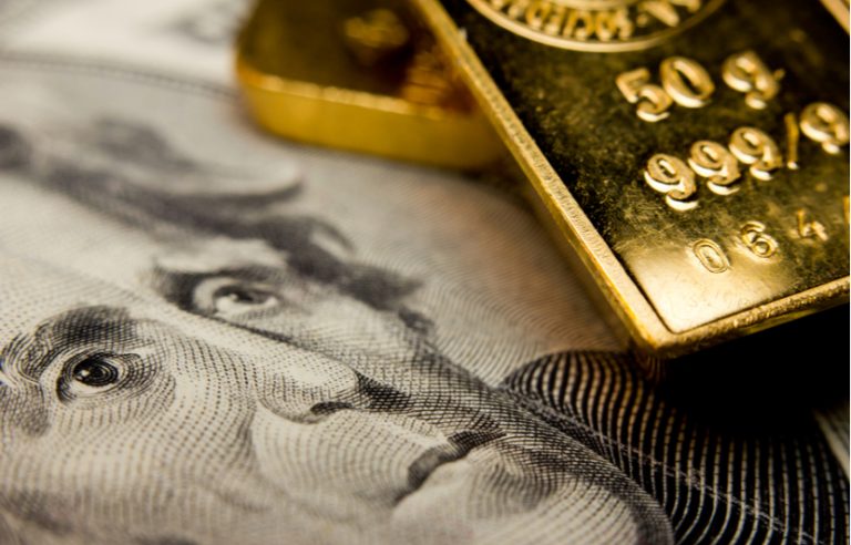 close up of gold bullion and hundred dollar bill