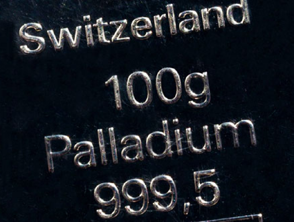 A close-up of a Palladium bar with the words "Switzerland 100g Palladium 99.95" engraved on it.