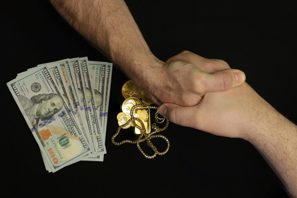 2 hands shaking during a business transaction for gold